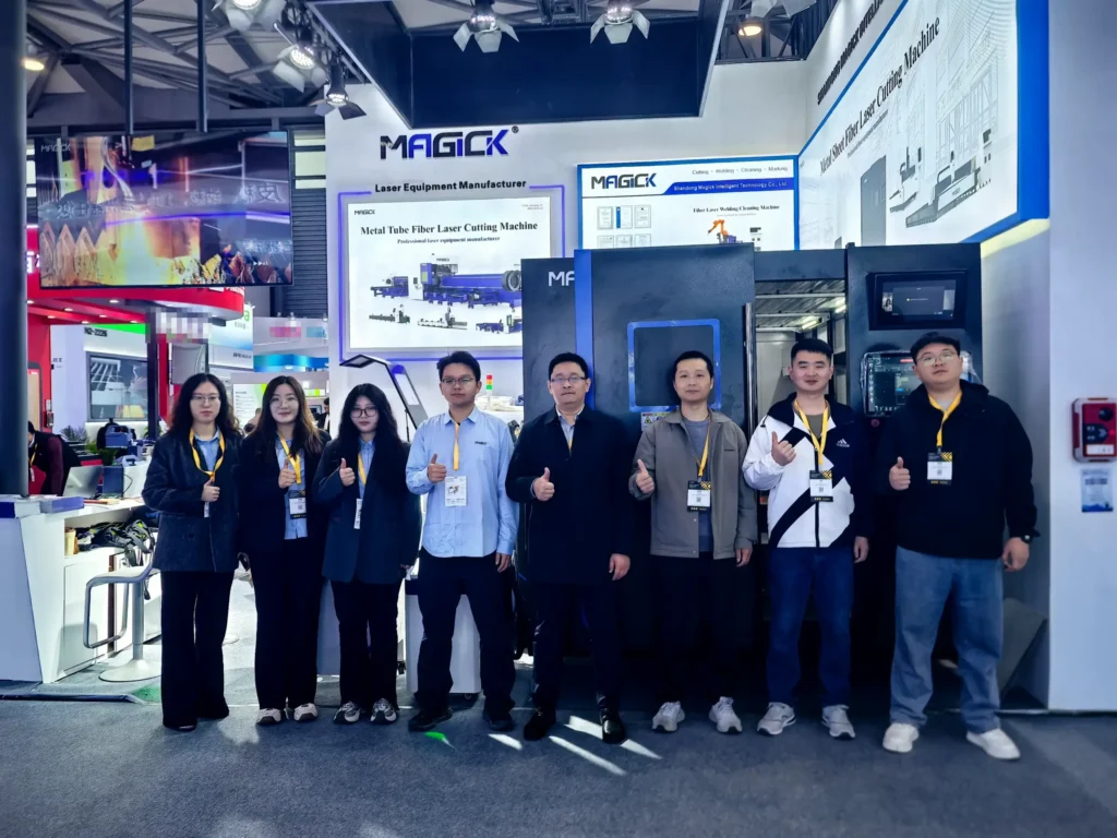 Magick Laser team celebrating a successful exhibit in front of Booth N2-2332 at Photonics China 2026. Backlit signs feature "12-80kW High Power Fiber Laser" and "MK-G Series" branding.